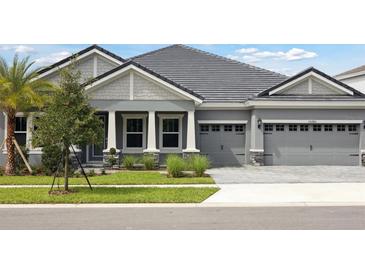 Charming gray home featuring a well-maintained lawn, neutral trim, and an attached two-car garage at 35280 Big Hawk Ln, Zephyrhills, FL 33541