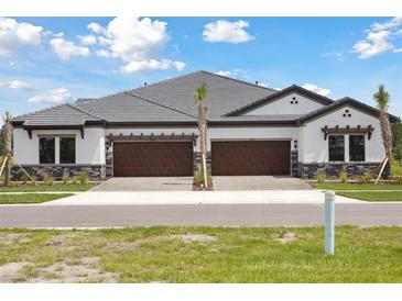 New construction townhome with a gray roof, two-car garage, and stone facade at 35571 Stableton Ln, Zephyrhills, FL 33541