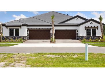 Charming exterior featuring stone accents, dark wood garage doors and a well-manicured lawn at 35579 Stableton Ln, Zephyrhills, FL 33541