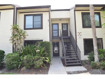 Two-story condo with cream siding, dark trim, outdoor stairways and green landscaping at 420 Moorings Cove Dr # 420, Tarpon Springs, FL 34689