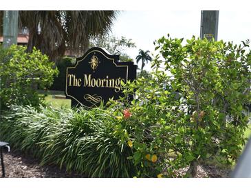 Community sign for The Moorings is surrounded by lush landscaping including palm trees at 420 Moorings Cove Dr # 420, Tarpon Springs, FL 34689