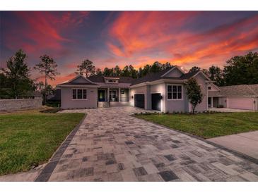 Stunning one-story home with a patterned paver driveway and a two-car garage set against a colorful sunset at 4522 Majestic Hills Loop, Brooksville, FL 34601