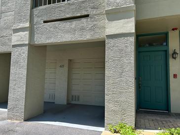 Exterior shot of condo with garage and green front door set in stucco wall at 622 Seascape Way, Tampa, FL 33602