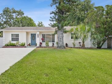 Charming single-story home with a well-manicured lawn, mature trees, and a lovely blue front door at 173 21St Se Ter, Largo, FL 33771