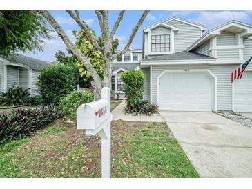 Charming townhome featuring a white garage door, a manicured lawn, and an American flag at 2456 Alhambra St, Clearwater, FL 33761