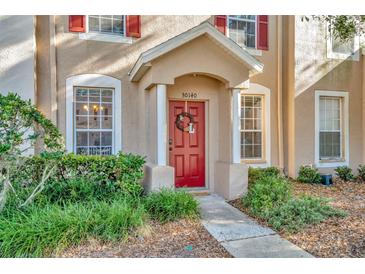 Charming townhome front door with red door, wreath and small front garden at 30140 Barnaby Ln, Wesley Chapel, FL 33543