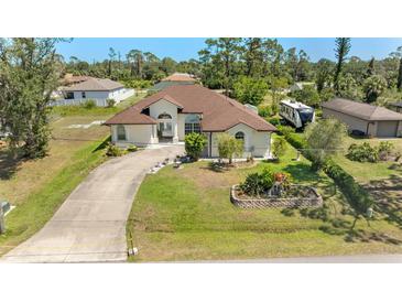Well-manicured lawn and landscaping accent this charming single Gathering home with a curved driveway at 3610 Woodbridge Ave, North Port, FL 34287