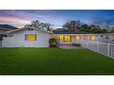 Charming single-story home featuring a well-manicured lawn and a classic white picket fence at dusk at 4709 W Fair Oaks Ave, Tampa, FL 33611