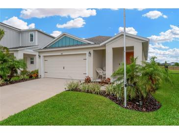 Charming single-story home featuring a two-car garage and a well-manicured lawn with lush landscaping at 5492 Summer Sunset Dr, Apollo Beach, FL 33572