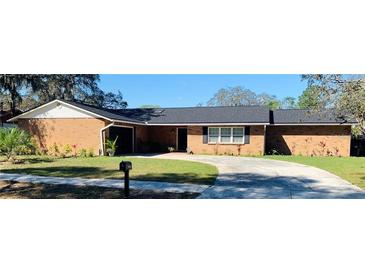 Charming brick home featuring a well-manicured lawn and a spacious driveway on a sunny day at 7014 Doreen St, Tampa, FL 33617