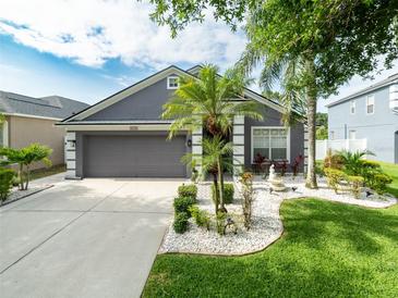 Charming home featuring a landscaped front yard with palm trees and a two-car garage at 8508 Canterbury Lake Blvd, Tampa, FL 33619
