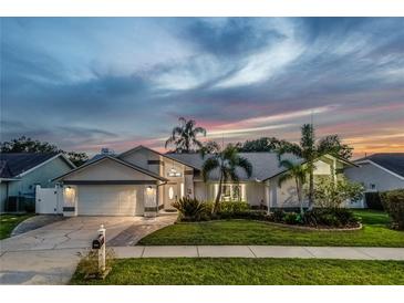 Charming single-story home with lush landscaping and a two-car garage at dusk at 1028 Wyndham Way, Safety Harbor, FL 34695
