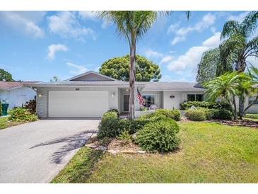 Charming single-story home featuring a lush landscaped front yard, inviting curb appeal, and a two-car garage at 2113 Malcolm Dr, Palm Harbor, FL 34684