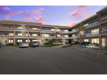 Multi-story condo building featuring brick accents, balconies, well-maintained landscaping, and ample parking at 2461 Rhodesian Dr # 37, Clearwater, FL 33763