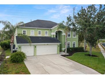 Two-story home with a three-car garage, landscaped yard, and a vibrant green exterior at 2832 Brinley Dr, Trinity, FL 34655