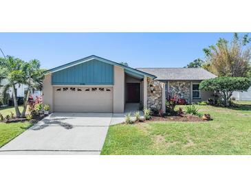 Charming single-story home with a stone facade, well-manicured lawn, and a two-car garage at 3105 Avocet Pl, Safety Harbor, FL 34695