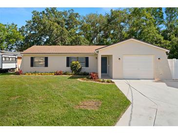 Charming single story home featuring manicured lawn, colorful landscaping, attached garage, and neutral color palette at 4549 Ontario Dr, New Port Richey, FL 34652