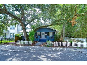 Charming home featuring mature trees, a welcoming porch and a classic white picket fence at 902 W Columbus Dr, Tampa, FL 33602