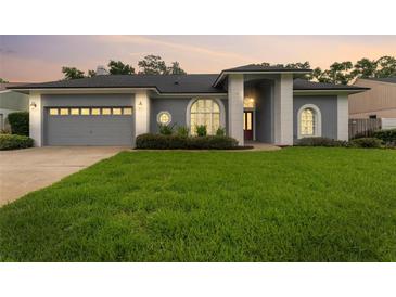 Charming single-story home featuring a manicured lawn and a gray stucco exterior at 15615 Indian Queen Dr, Odessa, FL 33556