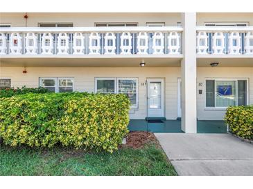 Inviting condo exterior with a well-kept lawn, garden foliage, and clearly marked unit numbers at 2452 Brazilia Dr # 18, Clearwater, FL 33763