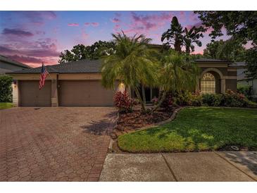 Charming home with a brick driveway, complemented by tropical landscaping and a serene residential neighborhood at 5101 Hartwell Loop, Land O Lakes, FL 34638