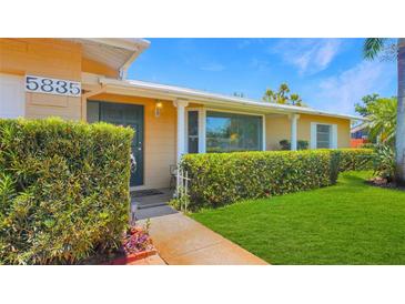 Charming home with a well-manicured lawn, lush hedges, and a welcoming front porch under a clear blue sky at 5835 29Th N Ave, St Petersburg, FL 33710