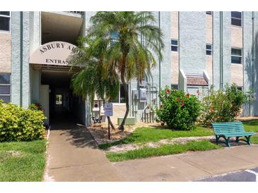 Entrance to building with landscaped lawn, bench, and shade trees at 801 83Rd N Ave # 209, St Petersburg, FL 33702