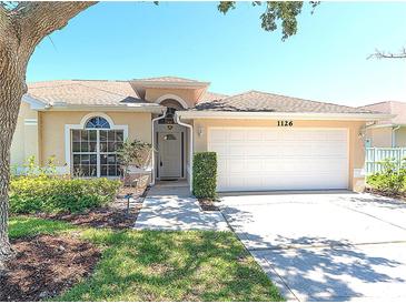 Inviting single-story home with a two-car garage, landscaped front yard and neutral color scheme at 1126 Haley Ln, Dunedin, FL 34698