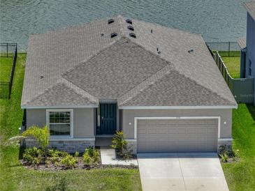 A single Gathering home has a grey shingle roof, front-entry garage and a lakeside view at 152 Bright Ibis Ave, Apollo Beach, FL 33572