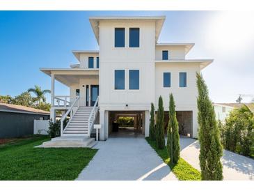 Modern white three-story home with a spacious covered parking area and well-manicured front lawn at 3752 Arkansas Ne Ave, St Petersburg, FL 33703