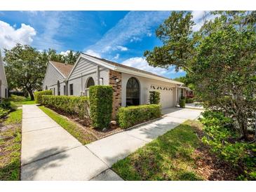 Well-maintained home featuring a lush green hedge, walkway and attached garage at 5524 Salem Square N Dr, Palm Harbor, FL 34685