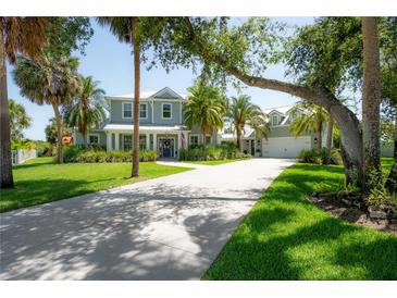Stunning two-story home with a lush green lawn, palm trees, and a long driveway at 8927 Key West Island Way, Riverview, FL 33578