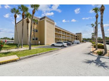 Condominium complex with neutral stucco, balconies, well-maintained landscaping, parking and palm trees at 1 Boca Ciega Point Blvd # 310, St Petersburg, FL 33708
