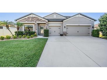 Charming single Gathering home featuring a stone facade, gray stucco and a well-manicured lawn at 12745 Moorish Pl, Spring Hill, FL 34610