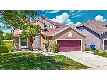 Charming two-story home featuring a landscaped front yard, palm tree, and a brick-paved driveway leading to a two-car garage at 14137 Wake Robin Dr, Brooksville, FL 34604