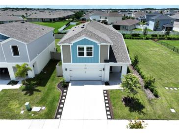 Two-story home boasts a well-maintained lawn, pristine driveway, and a charming blue and gray exterior at 34056 Scarlet Sage Ct, Wesley Chapel, FL 33545