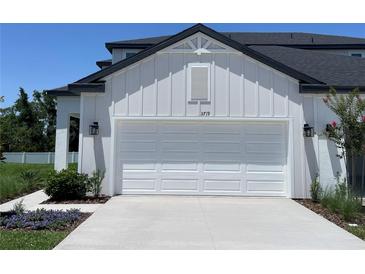 A white, two-car garage with an immaculate driveway is found on the exterior of this modern home at 3719 Nandina Cir, Sun City Center, FL 33573
