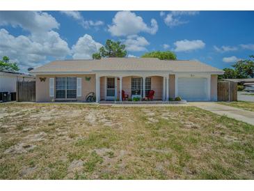Charming single-story home with a covered front porch and attached one-car garage, surrounded by a lawn at 4150 Woodsville Dr, New Port Richey, FL 34652