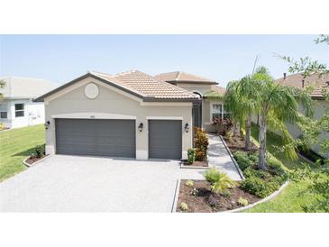 Beautiful home exterior with a tile roof, paver driveway, two car garage, and professional landscaping at 4888 Sevilla Shores Dr, Wimauma, FL 33598
