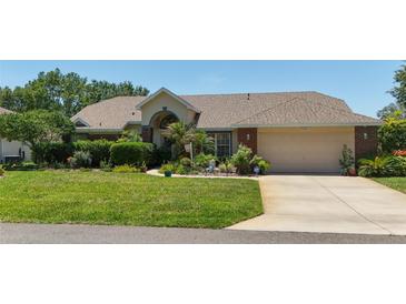 Charming single Gathering home featuring a well-manicured lawn, lush landscaping, and a welcoming two-car garage at 5465 Chestnut Ridge Rd, Dade City, FL 33523