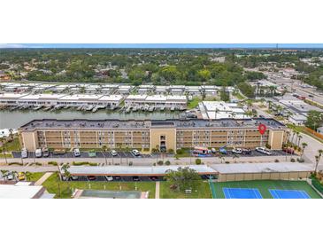 Aerial view showcases a waterfront condo building with boat docks, parking, tennis courts and a pool at 1 Boca Ciega Point Blvd # 215, St Petersburg, FL 33708