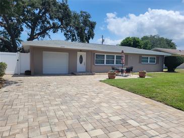 Charming single-story home with a paver driveway, attached garage, and a manicured lawn at 13725 Bermuda Dr, Seminole, FL 33776
