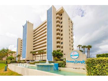 Stunning view of the Ocean Sands building with meticulous landscaping and beautiful water features in the foreground at 14950 Gulf Blvd # 603, Madeira Beach, FL 33708