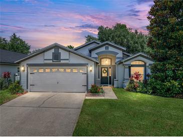 Charming one-story home featuring a manicured lawn, lovely landscaping, and an attached two-car garage at 18003 Arbor Crest Dr, Tampa, FL 33647