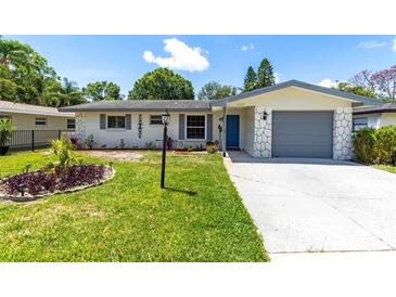 Charming home featuring an inviting front yard with a well-maintained lawn and landscaped garden beds at 1809 Elmwood Dr, Oldsmar, FL 34677