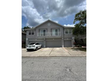 Three-story townhouse with gray facade, balconies, and attached garages; white car parked in front at 27653 Pleasure Ride Loop, Wesley Chapel, FL 33544