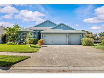 Charming single-story home with a well-manicured lawn, mature trees, and a three-car garage at 378 Wood Chuck Ave, Tarpon Springs, FL 34689
