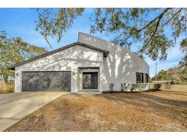 Beautifully landscaped front exterior of a home with a gray garage and a distinctive curved architectural feature at 5526 Southernview Dr, Zephyrhills, FL 33541