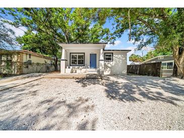 Bungalow with blue door, set on a gravel yard beneath mature trees at 8504 N 17Th St, Tampa, FL 33604