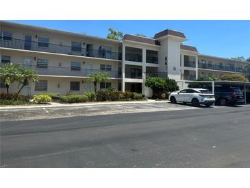Multi-story condo building featuring balconies, parking, and tropical landscaping, with address number prominently displayed at 861 Maple Ct # 104, Dunedin, FL 34698